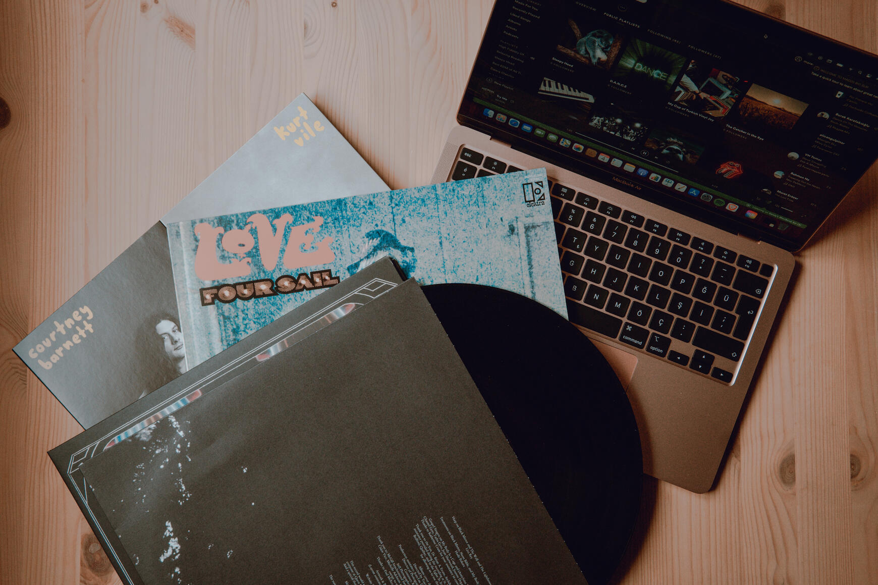 Vinyl records and a computer showcasing a playlist.